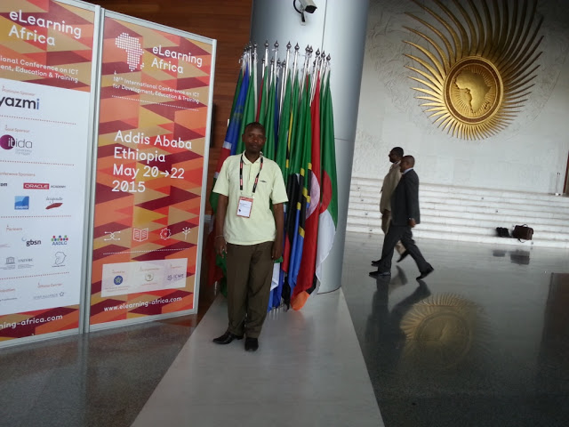 Moses Wamanga in-front of the African flags at the African Union headquarters.